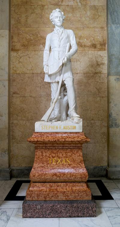 sculpture of a man standing with a rifle in front of him above a Texas marble stand 